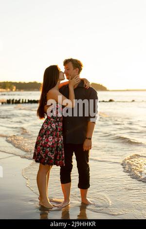 Junges Paar, das sich an sonnigen Tagen am Strand an den Nasen reibt Stockfoto