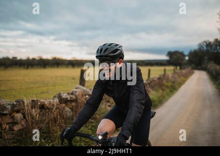 Glücklicher Mann mit Fahrradhelm, der Fahrrad auf der Straße fährt Stockfoto