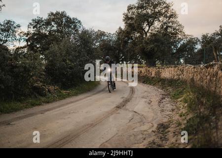 Mann, der bei Sonnenaufgang Fahrrad auf der Straße fährt Stockfoto