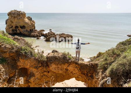 Unbeschwerter Mann mit ausgestreckten Armen, der an sonnigen Tagen vor dem Meer steht Stockfoto