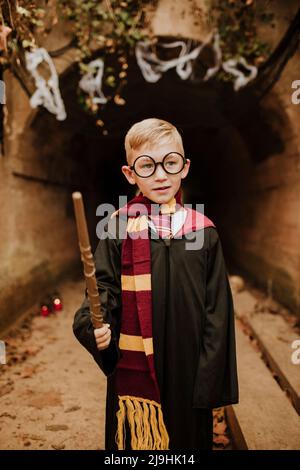 Junge mit Kostüm und Zauberstab vor dem Tunnel an Halloween Stockfoto