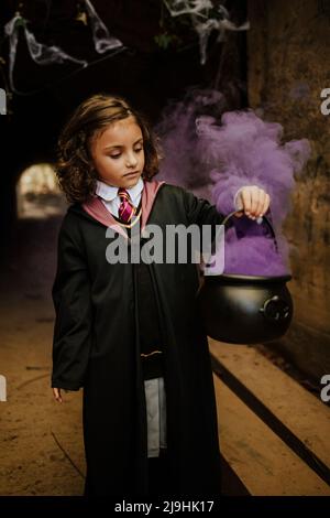 Nettes Mädchen hält Kessel mit Hexen brauen tragen Hexen Kostüm in gruseligen Tunnel Stockfoto