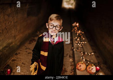 Lächelnder Junge im Kostüm im Tunnel stehend Stockfoto