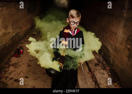 Junge mit Kessel und Zauberabteilung, der inmitten eines gelben Tunnels steht Stockfoto