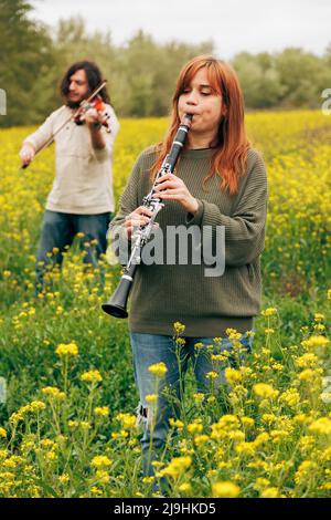 Mann und Frau üben Musikinstrumente im Blumenfeld Stockfoto