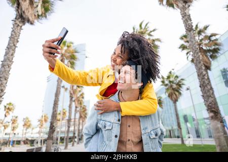 Lächelnde Frau, die Selfie mit einem Mann macht, der Huckepack fährt Stockfoto