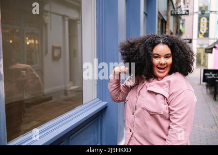 Glückliche Frau, die beim Fenster die Haare wirft Stockfoto