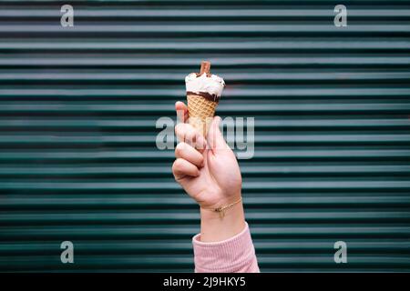 Hand einer Frau, die Eiscreme vor dem Verschluss hält Stockfoto