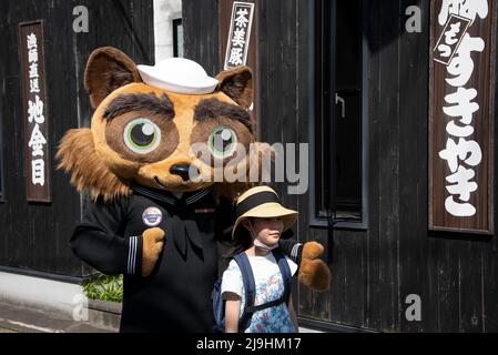 Shimoda, Japan. 22.. Mai 2022. Yoko-pon, das offizielle Maskottchen von Commander, U.S. Navy Fleet Activities Yokosuka, posiert mit einem jungen japanischen Mädchen während des jährlichen Shimoda Black Ship Festivals 83. am 22. Mai 2022 in Shimoda, Japan. Das Shimoda Black Ship Festival, oder Shimoda Kurofune, feiert die Ankunft von Commodore Matthew Perry und die Öffnung Japans nach außen. Kredit: MC1 Kaleb J. Sarten/U.S. Air Force/Alamy Live News Stockfoto