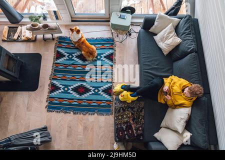 Junge sitzt auf dem Sofa mit Smartphone im Wohnzimmer zu Hause Stockfoto