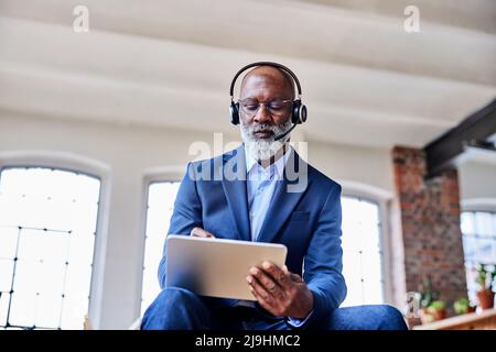 Geschäftsmann mit Headset, der zu Hause einen digitalisierten Stift auf einem Tablet-PC verwendet Stockfoto