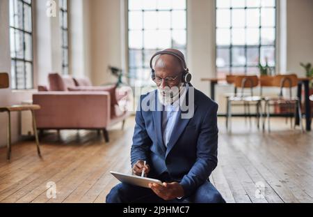 Geschäftsmann mit Headset, der zu Hause einen Tablet-PC mit digitalisiertem Stift verwendet Stockfoto