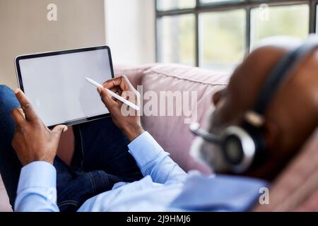 Geschäftsmann, der zu Hause einen digitalisierten Stift auf einem Tablet-PC verwendet Stockfoto