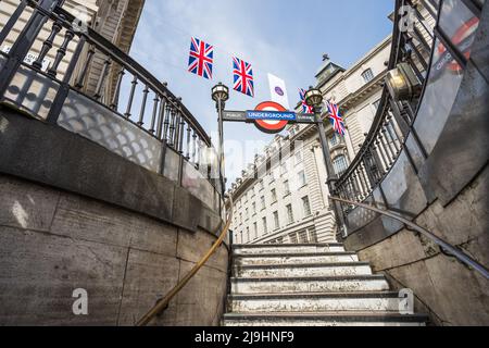 Blick auf die Union Jack Flaggen über einem Eingang der U-Bahnstation Piccadily Circus im Mai 2022, als sich London auf die Queens Platin vorbereitete Stockfoto