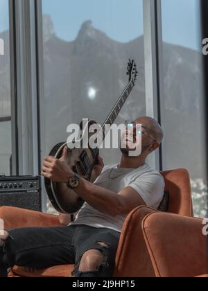 Junger kahler Mann spielt Gitarre und lächelt vor Aufregung Stockfoto