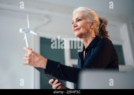 Geschäftsfrau, die im Büro das Windenergieanlagenmodell analysiert Stockfoto