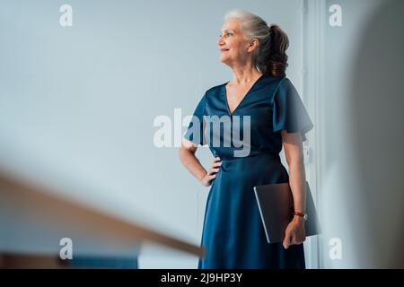 Lächelnde Geschäftsfrau mit Laptop im Büro Stockfoto