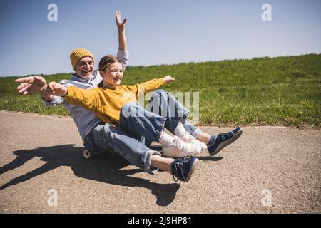 Glücklicher Großvater genießt Skateboarding mit Enkelin auf der Straße Stockfoto