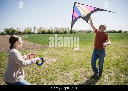 Großvater lehrt Enkelin fliegenden Drachen auf dem Feld Stockfoto