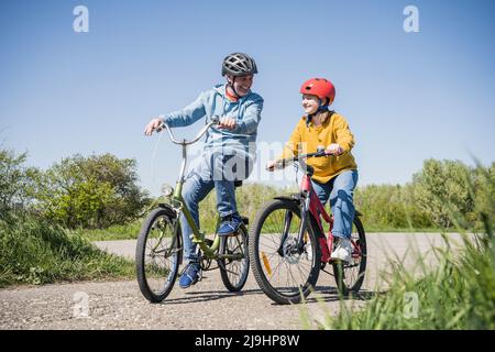 Glücklicher Großvater mit Enkelin, die auf dem Wanderweg radelt Stockfoto