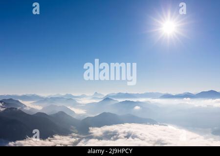 Deutschland, Bayern, die Sommersonne scheint über den Gipfeln der bayerischen Voralpen, die von dichtem Nebel umhüllt sind Stockfoto