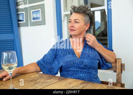 Lächelnde Frau mit einem Glas Wein am Tisch Stockfoto