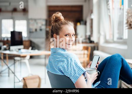 Fröhliche Geschäftsfrau, die zu Hause über die Schulter schaut Stockfoto