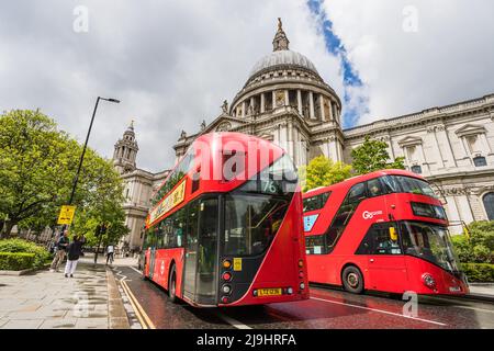 Im Mai 2022 fahren zwei leuchtend rote Londoner Busse vor der St. Pauls Cathedral im Herzen Londons vorbei. Stockfoto