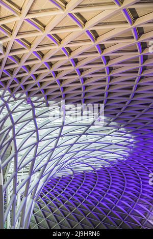 Eine Nahaufnahme der abstrakten Decke über dem Bahnhof Kings Cross, die im Mai 2022 in violetten Lichtern beleuchtet wurde. Stockfoto