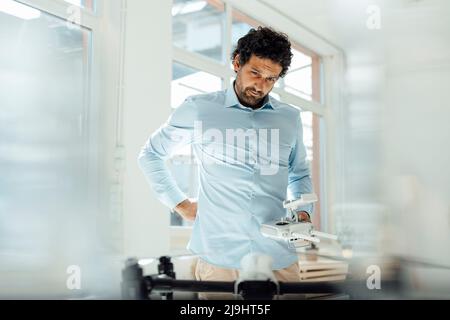 Geschäftsmann mit Fernbedienung und Blick auf die Drohne im Büro Stockfoto