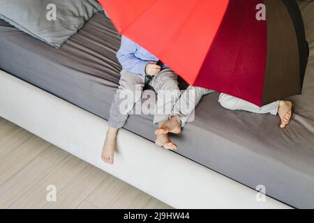 Zwillingsschwestern sitzen unter einem Sonnenschirm im Schlafzimmer Stockfoto