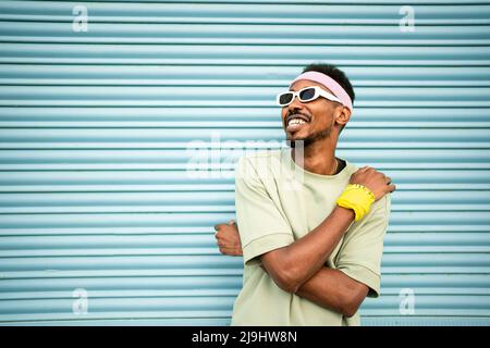 Fröhlicher Mann mit Brille und Stirnband vor blauem Verschluss Stockfoto
