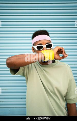 Junger Mann, der den Mund mit der Hand vor dem blauen Verschluss bedeckt Stockfoto