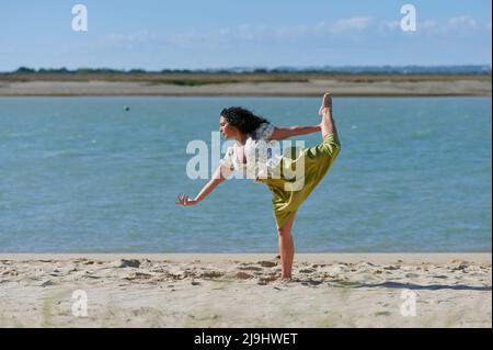 Junge Frau, die am Strand an der Küste tanzt Stockfoto