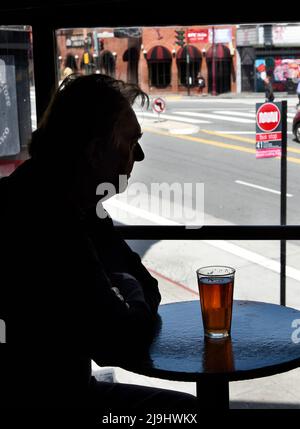 Ein Mann genießt ein Bier im Vesuvio Cafe, einer der Wahrzeichen der amerikanischen Bar im North Beach-Viertel von San Francisco, Kalifornien. Stockfoto