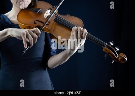 Reife Frau spielt Geige vor schwarzem Hintergrund Stockfoto