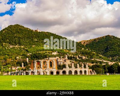 Gubbio, antike Ruinen des römischen Amphitheaters mit dem mittelalterlichen Dorf im Hintergrund, Umbrien, Mittelitalien Stockfoto