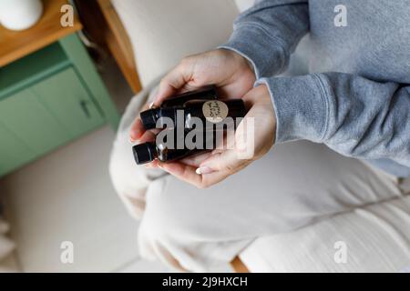 Frau mit Flaschen aus ätherischem Öl zu Hause Stockfoto