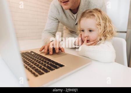 Nette Tochter mit Vater mit Laptop zu Hause Stockfoto