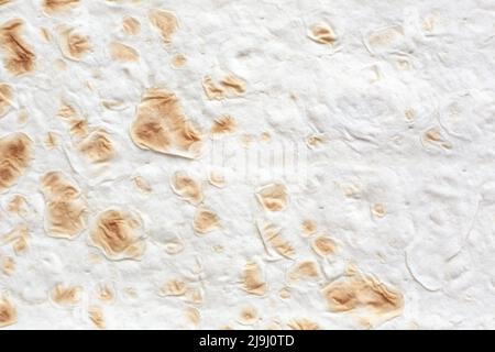 Teigstruktur von armenischem Lavaschbrot, natürlicher beiger Hintergrund mit goldbraunen Einschlüssen. Stockfoto