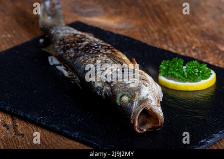 Bass mit Zitrone auf schwarzem Schiefer Stockfoto