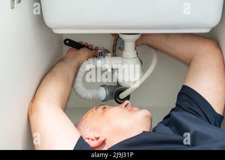 Do-it-yourself Sanitär Reparatur von einem Mann unter dem Waschbecken Stockfoto