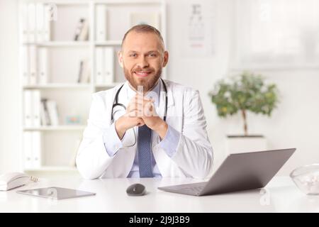 Ein Praktizierender aus der Praxis sitzt in einem Büro und lächelt der Kamera zu Stockfoto