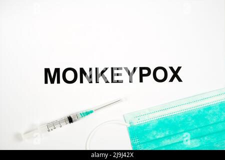 NAME der MONKEYPOX-Infektion auf Papier mit Spritze und medizinischer Maske. Konzept. Stockfoto