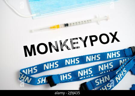 NAME der MONKEYPOX-Infektion auf Papier mit Spritze und NHS-Trageschlaufe daneben. Konzept. Stafford, Großbritannien, 23. Mai 2022. Stockfoto