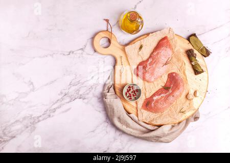 Rohe Kalbsschnitzel bereit zum Kochen auf einem runden Schneidebrett Stockfoto