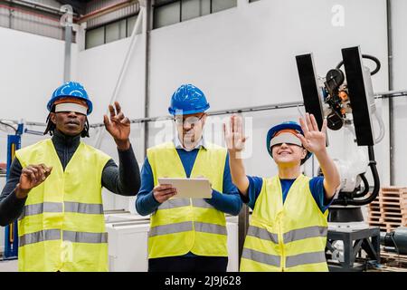 Multiethnische Ingenieure mit Augmented Reality futuristische Brille in der Automatisierungs- und Robotikfabrik - Neues Industrietechnologiekonzept Stockfoto