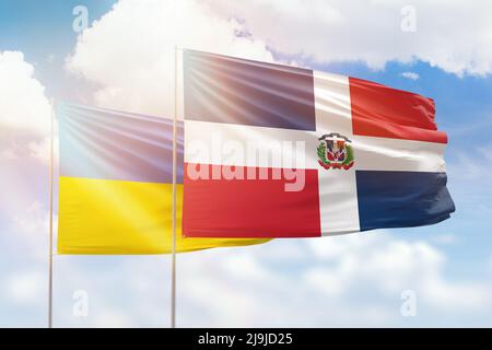 Sonniger blauer Himmel und Flaggen der dominikanischen republik und der ukraine Stockfoto