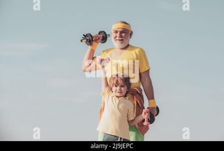 Gesunder Familienleben. Großvater und kleiner Enkel üben im Freien Hantelübungen. Motivations- und Sportbeispielkonzept. Stockfoto