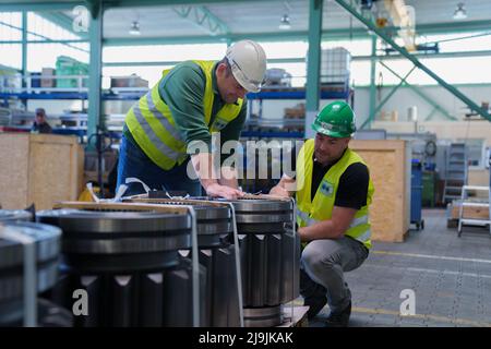 Kehl, Deutschland. 28. April 2022. Die Mitarbeiter der Herrenknecht AG Rebuild Services in Kehl, Patrick Decouval (l) und Dominic Schultze, betrachten Antriebsritzel eines Schneidantriebs. Hier zerlegt der Tunnelbohrmaschinenhersteller alte Maschinen in ihre Einzelteile, konditioniert sie und montiert sie wieder. (To dpa 'alt in neu verwandeln - wo Tunnelbohrmaschinen auseinandergerissen werden') Quelle: Benedikt Spether/dpa/Alamy Live News Stockfoto